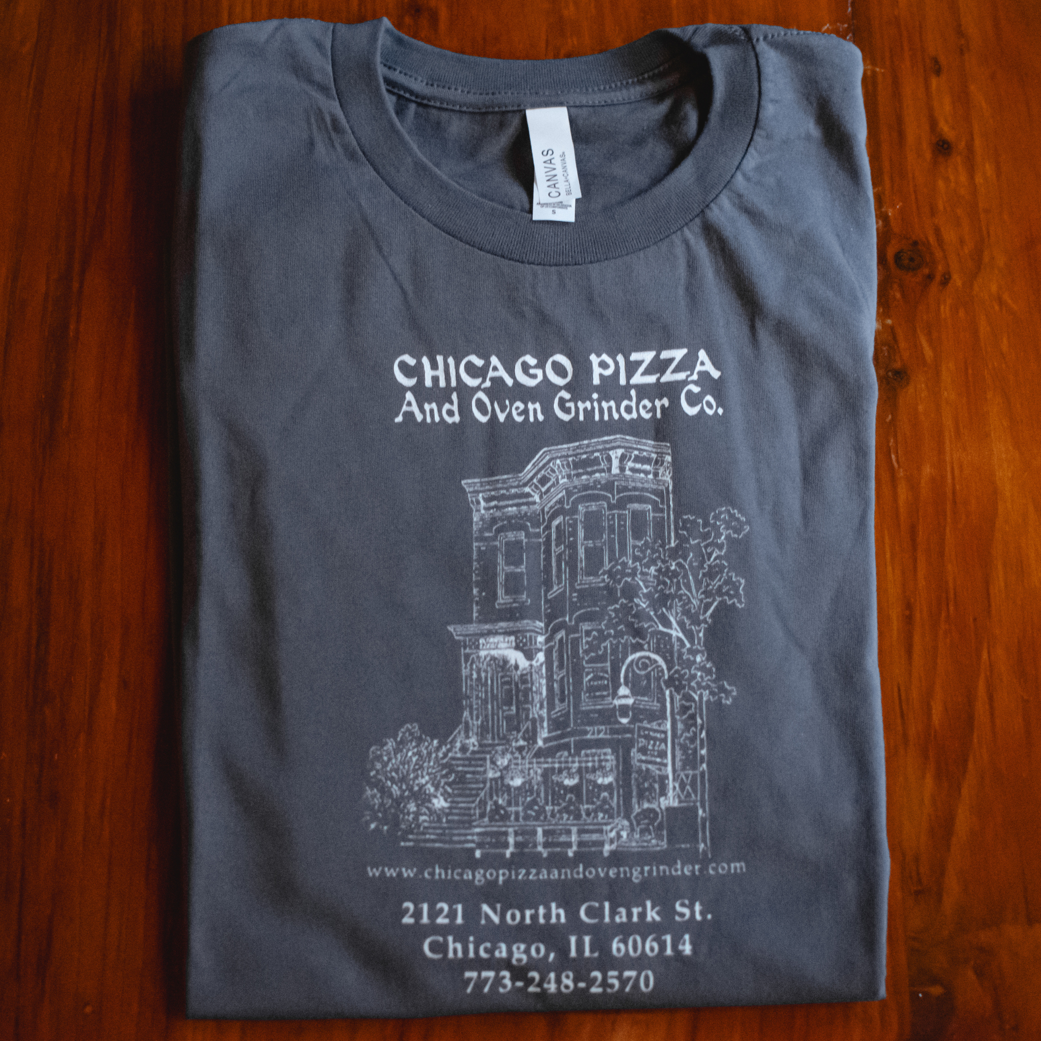 Folded gray t-shirt with white text and graphics on a wooden surface