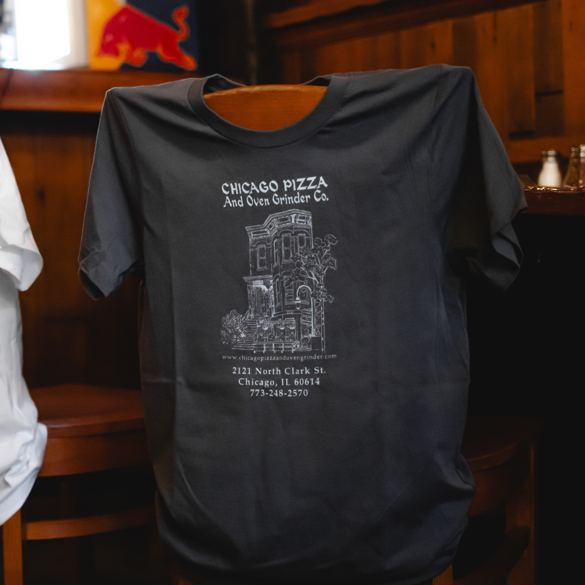 Black t-shirt with white text and graphics on a wooden chair